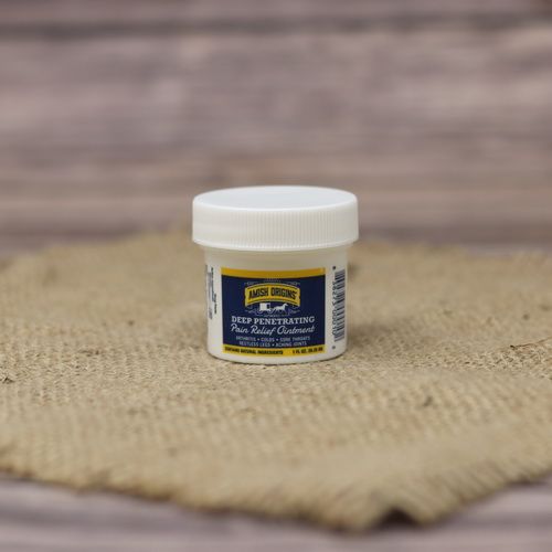 A 1 oz container of Amish Origins Deep Penetrating Pain Relief Ointment, set on rustic burlap with a wooden background.