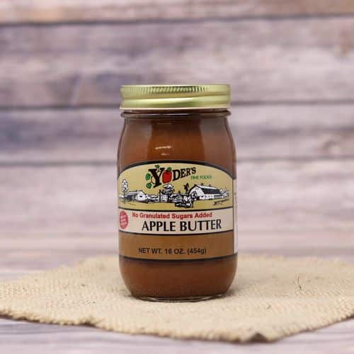 A pint size glass jar of Yoder's Fine Foods No Sugar Added Apple Butter, on rustic burlap with a wooden background.