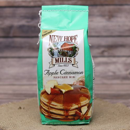 A slender green bag of Apple Cinnamon Pancake Mix on rustic burlap with a wooden background.