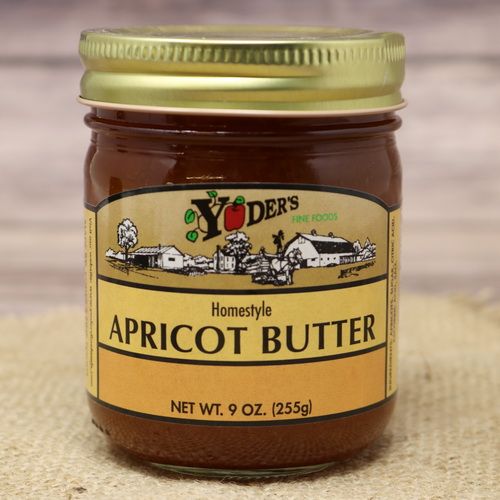 A 9 oz glass jar of Yoder's Fine Foods Apricot Butter, on rustic burlap with a wooden background.