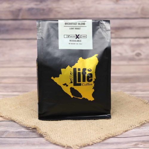 A Black bag of Better Life Coffee Breakfast Blend on rustic burlap with a wooden background.