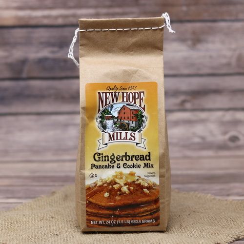 A brown bag of Gingerbread Pancake Mix on rustic burlap with a wooden background.