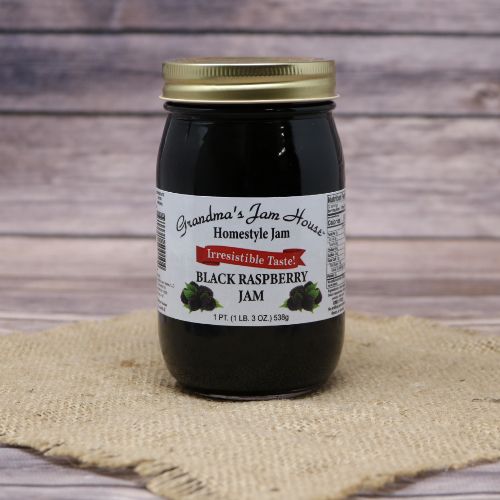 A pint size glass jar of Grandma's Jam House Black Raspberry Jam, on rustic burlap with a wooden background.
