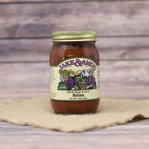 A pint size glass jar of Jake & Amos Black Bean & Corn Salsa, on rustic burlap with a wooden background.