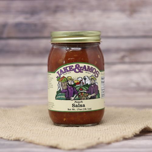 A pint size glass jar of Jake & Amos Peach Salsa, on rustic burlap with a wooden background.