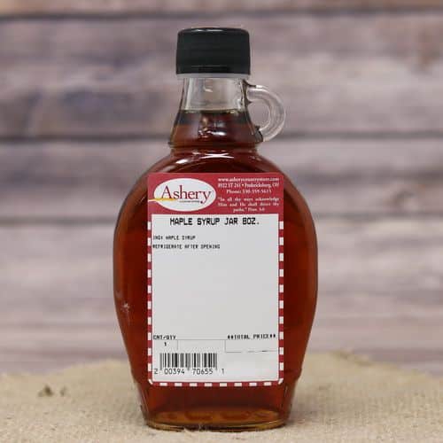 An 8 oz glass jar of Pure Ohio Maple Syrup, set on rustic burlap with a wooden background.
