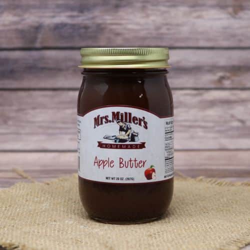 A 20 oz glass jar of Mrs. Miller's Apple Butter, on rustic burlap with a wooden background.