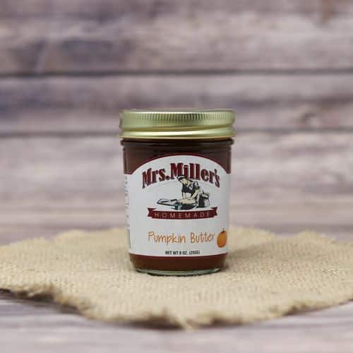 A 9oz glass jar of Mrs. Miller's Pumpkin Butter, on rustic burlap with a wooden background.