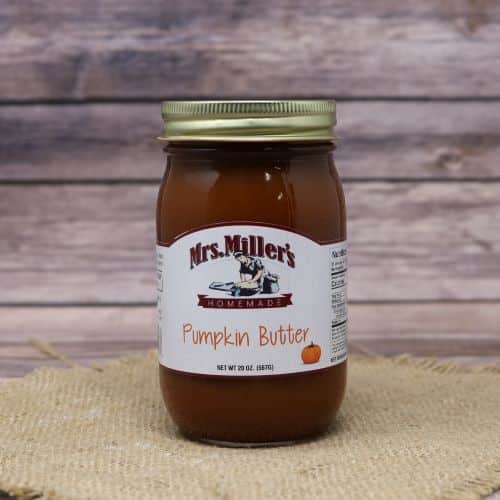 A 20 oz glass jar of Mrs. Miller's Pumpkin Butter, on rustic burlap with a wooden background.