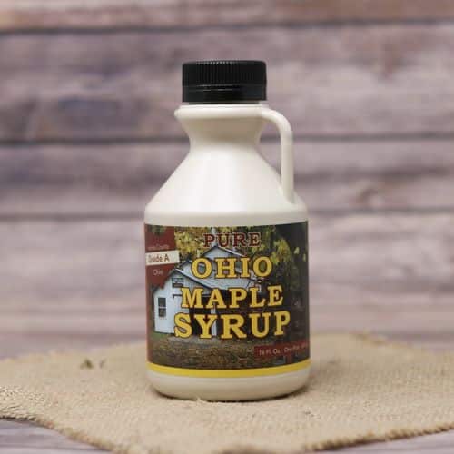 A pint sized bottle of Pure Ohio Maple Syrup, set on rustic burlap with a wooden background.