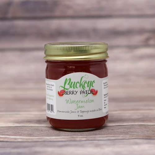 A glass jar of Buckeye Berry Patch Watermelon Jam with a wooden background.