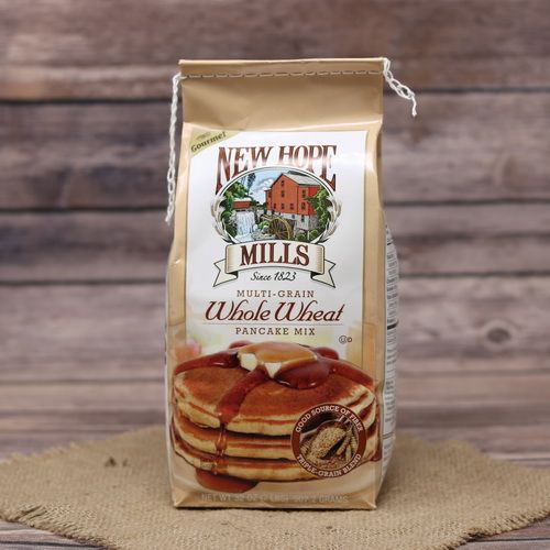 A tall brown bag of Whole Wheat Pancake Mix on rustic burlap with a wooden background.
