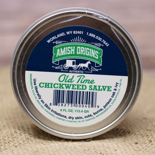 A metal container of Amish Origins Chickweed Salve, set on rustic burlap with a wooden background.