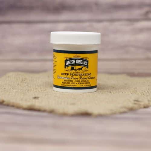 A 3.5 oz container of Amish Origins Greaseless Pain Relief Cream, set on rustic burlap with a wooden background.