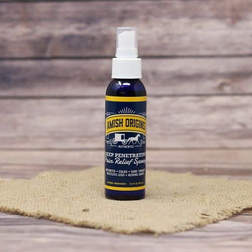A spray bottle of Amish Origins Deep Penetrating Pain Relief Spray, set on rustic burlap with a wooden background.