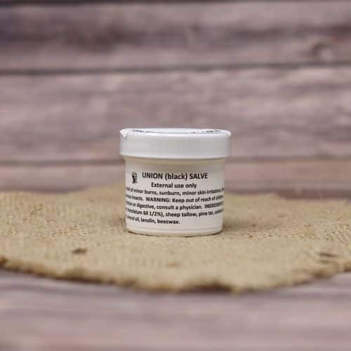 A 2 oz container of Union Black Salve, set on rustic burlap with a wooden background.
