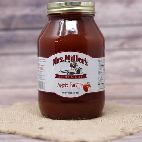 A 36 oz glass jar of Mrs. Miller's Apple Butter, on rustic burlap with a wooden background.