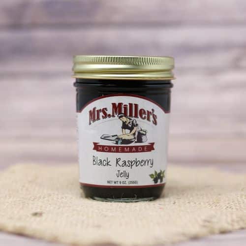 A 9 oz glass jar of Mrs. Miller's Black Raspberry Jelly, on rustic burlap with a wooden background.