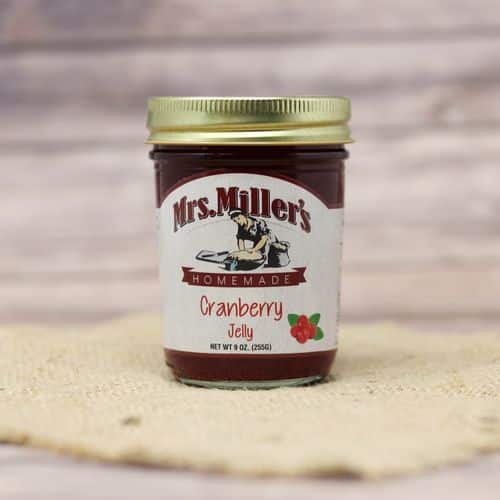 A 9 oz glass jar of Mrs. Miller's Cranberry Jelly, on rustic burlap with a wooden background.
