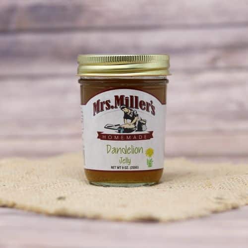 A 9 oz glass jar of Mrs. Miller's Dandelion Jelly, on rustic burlap with a wooden background.