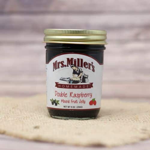 A 9 oz glass jar of Mrs. Miller's Double Raspberry Jelly, on rustic burlap with a wooden background.