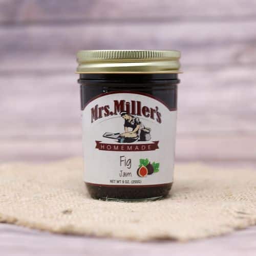 A 9 oz glass jar of Mrs. Miller's Fig Jam, on rustic burlap with a wooden background.
