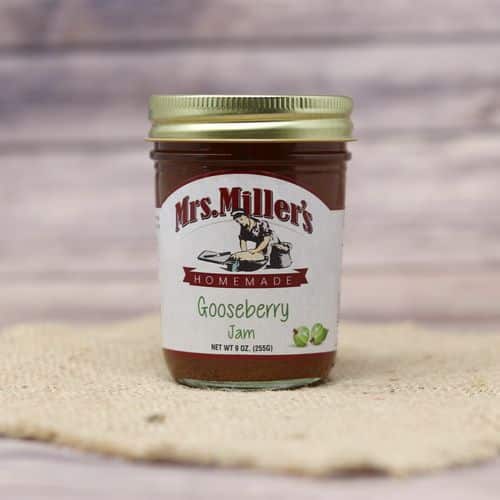 A 9 oz glass jar of Mrs. Miller's Gooseberry Jam, on rustic burlap with a wooden background.