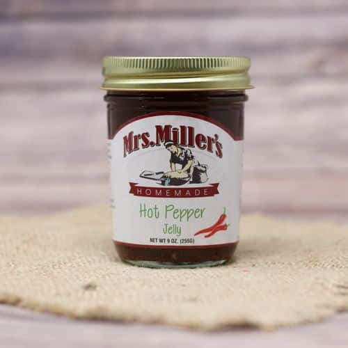 A 9 oz glass jar of Mrs. Miller's Hot Pepper Jelly, on rustic burlap with a wooden background.