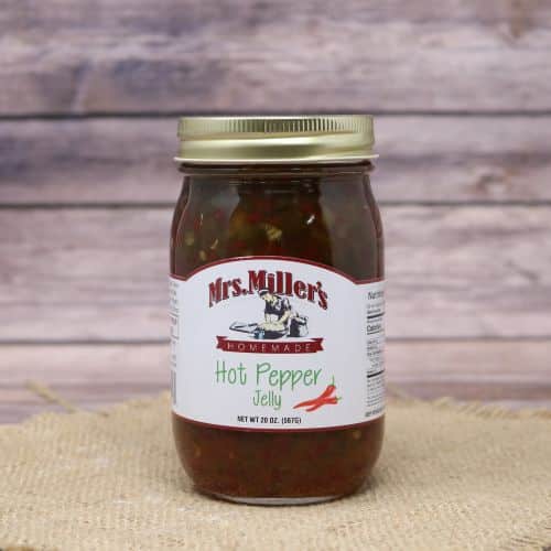 A 20 oz glass jar of Mrs. Miller's Hot Pepper Jelly, on rustic burlap with a wooden background.