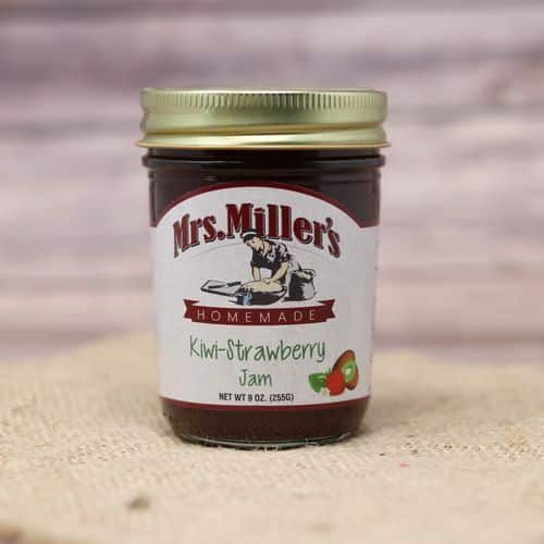 A 9 oz glass jar of Mrs. Miller's Kiwi Strawberry Jam, on rustic burlap with a wooden background.