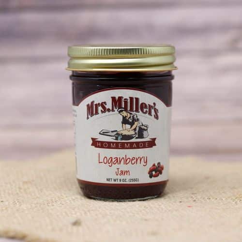 A 9 oz glass jar of Mrs. Miller's Loganberry Jam, on rustic burlap with a wooden background.