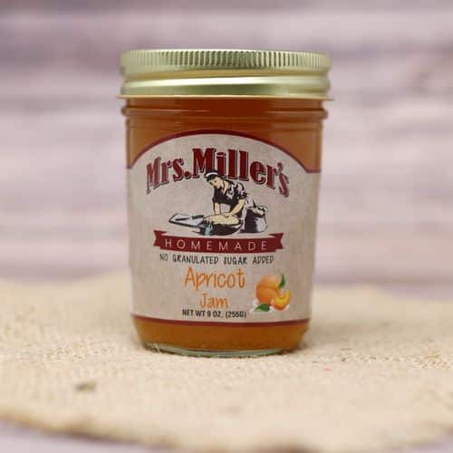 A 9 oz glass jar of Mrs. Miller's No Sugar Added Apricot Jam, on rustic burlap with a wooden background.
