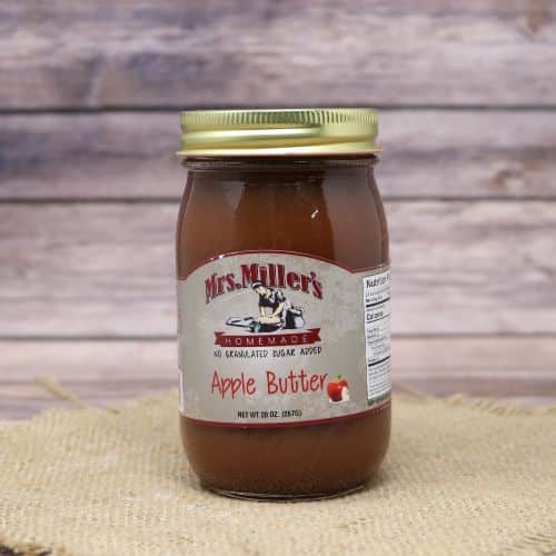 A 20 oz glass jar of Mrs. Miller's No Sugar Added Apple Butter, on rustic burlap with a wooden background.