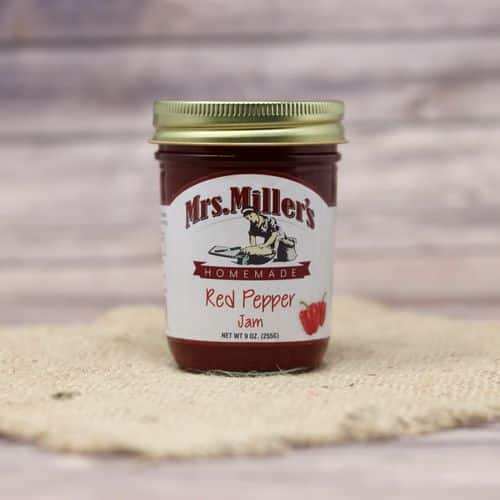 A 9 oz glass jar of Mrs. Miller's Red Pepper Jam, on rustic burlap with a wooden background.