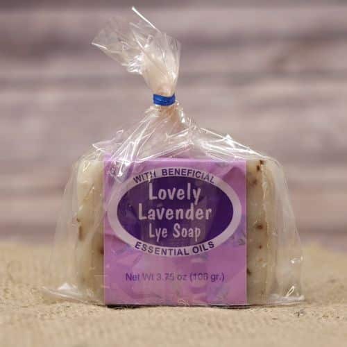 Lavender scented bar soap in a plastic bag closed with a twist tie, set on rustic burlap with a wooden background.