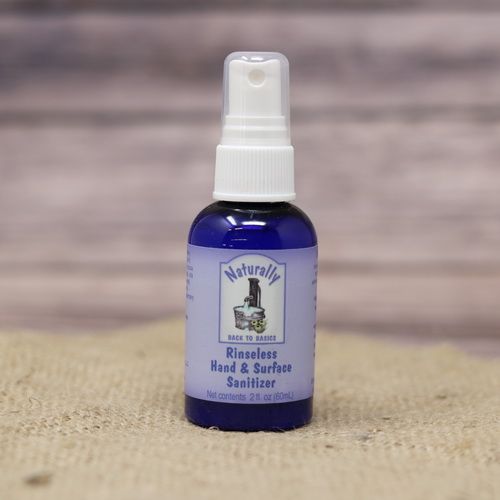 A 2 oz spray bottle of Rinseless Hand Sanitizer, set on rustic burlap with a wooden background.