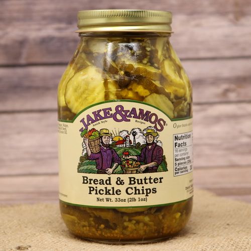 A quart size glass jar of Jake & Amos Bread & Butter Pickle Chips, on rustic burlap with a wooden background.