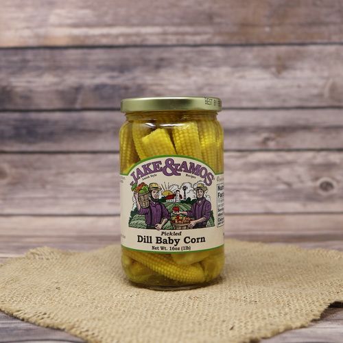 A pint size glass jar of Jake & Amos Pickled Dill Baby Corn, on rustic burlap with a wooden background.
