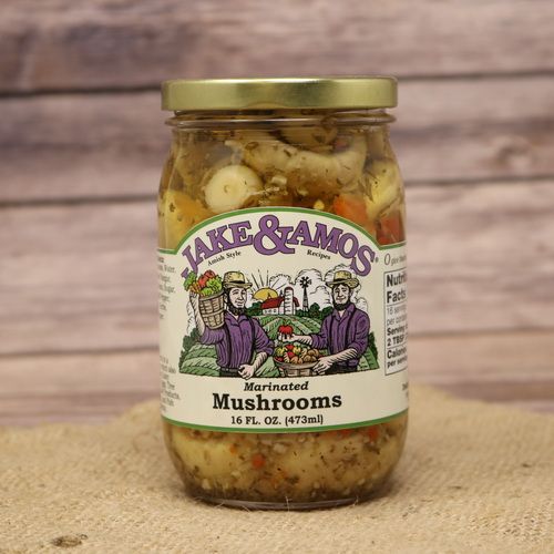 A pint size glass jar of Jake & Amos Marinated Mushrooms, on rustic burlap with a wooden background.