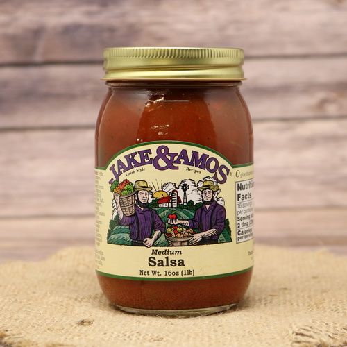 A pint size glass jar of Jake & Amos Medium Salsa, on rustic burlap with a wooden background.