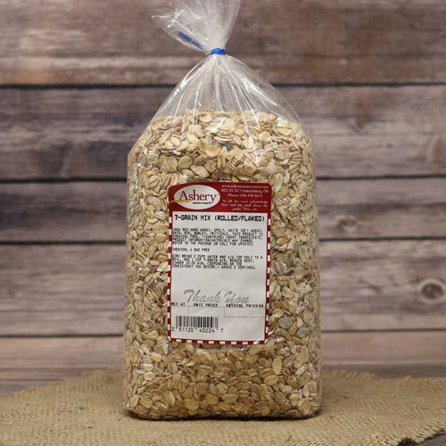 A bag of Rolled & Flaked 7-Grain Mix in a clear bag, closed with a twist tie, with a rustic wooden background on burlap.