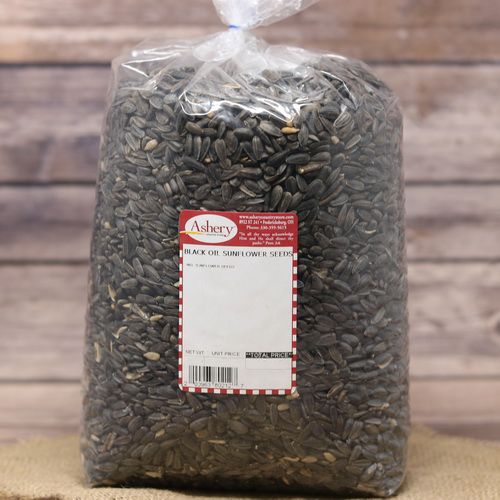 A large clear plastic bag of Black Oil Sunflower Seeds sealed with a twist tie on rustic burlap with a wooden background.