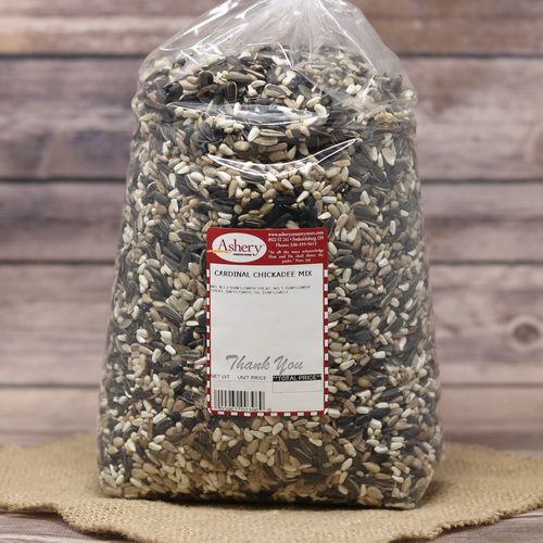 A large clear plastic bag containing Cardinal Chickadee Mix sealed with a twist tie on rustic burlap with a wooden background.