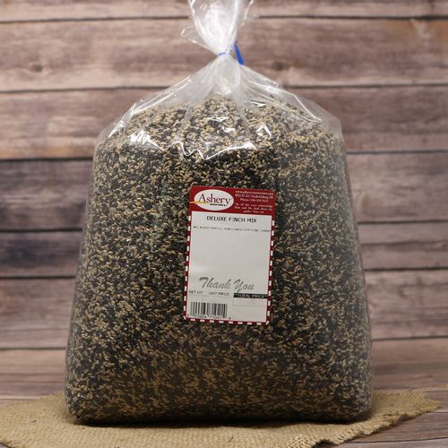 A large clear bag of Deluxe Finch Mix sealed with a twist tie on rustic burlap with a wooden background.
