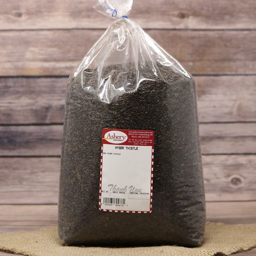 A large clear plastic bag of Nyjer Thistle for birds on rustic burlap with a wooden background.