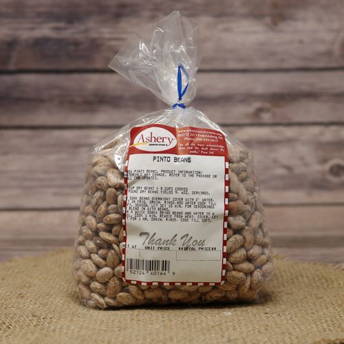 A clear plastic bag of dried Pinto Beans on rustic burlap with a wooden background.