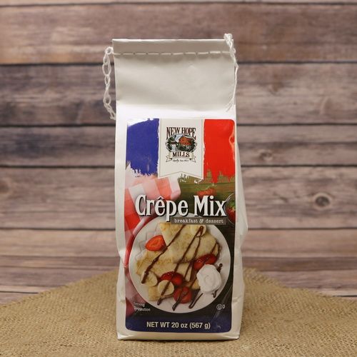 A small white bag with a colorful sticker label of Crepe Mix on rustic burlap with a wooden background.