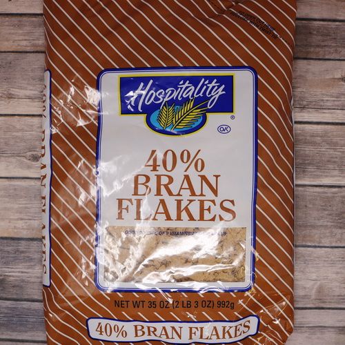 A large bag brown bag with brown writing of 40% Bran Flakes on rustic burlap with a wooden background.