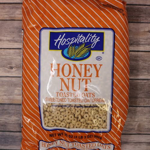 An orange bag of Honey Nut Toasted Oats on rustic burlap with a wooden background.