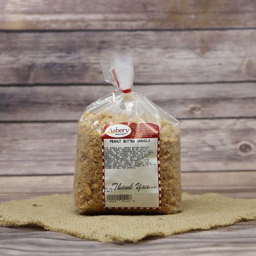 A clear bag of Peanut Butter Granola sealed with a twist tie on rustic burlap with a wooden background.